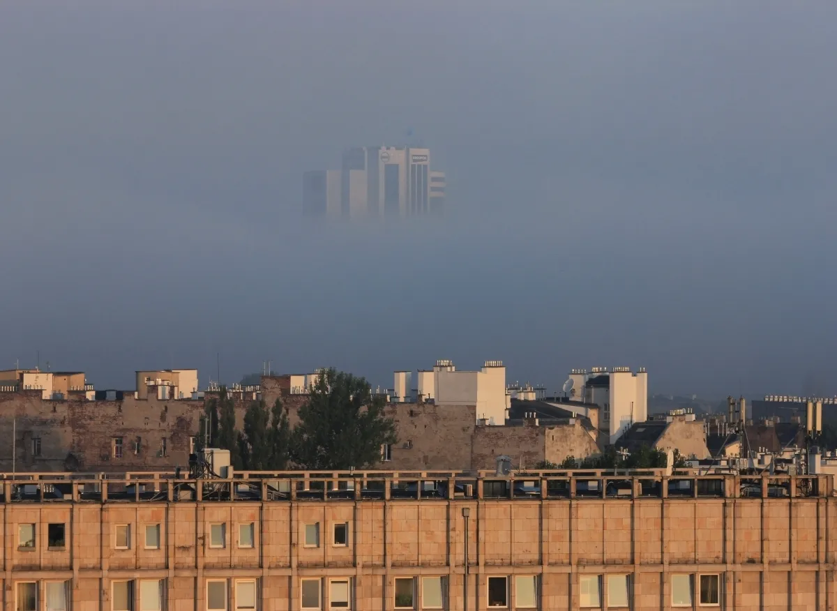 Distant high-rise tower emerging from fog above city rooftops